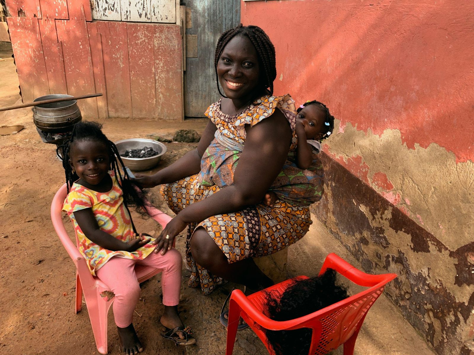A mother and her children at home, one holding a reading book